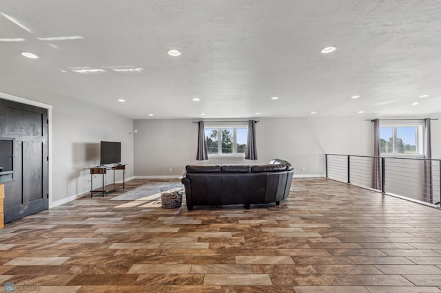 living area featuring recessed lighting, baseboards, and a textured ceiling