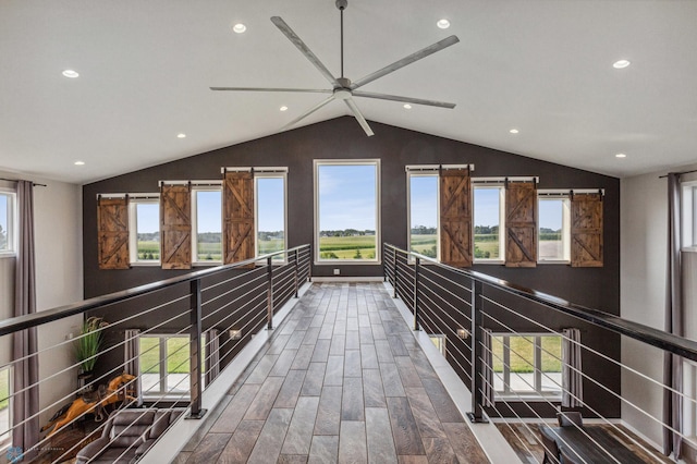 hallway with lofted ceiling, wood finished floors, and a wealth of natural light