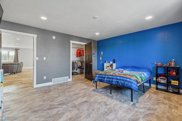 bedroom featuring visible vents, a walk in closet, baseboards, recessed lighting, and wood finished floors