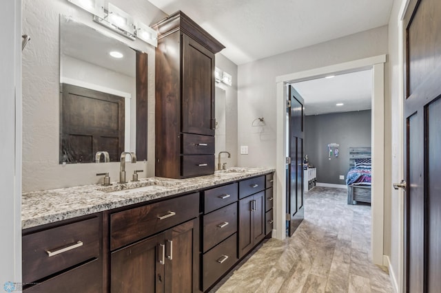 full bathroom with a sink, baseboards, ensuite bath, and double vanity