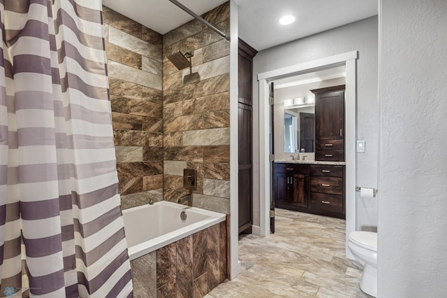 bathroom with tiled shower / bath, toilet, vanity, and a textured wall