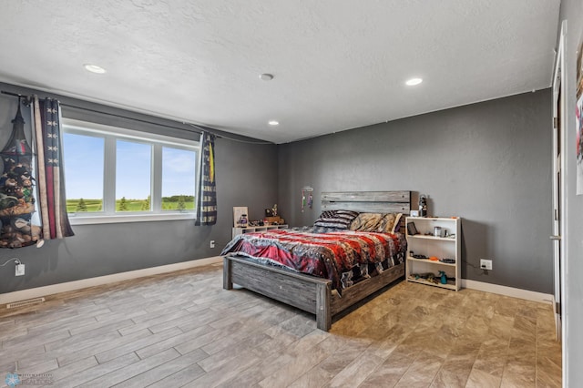 bedroom with visible vents, a textured ceiling, and baseboards