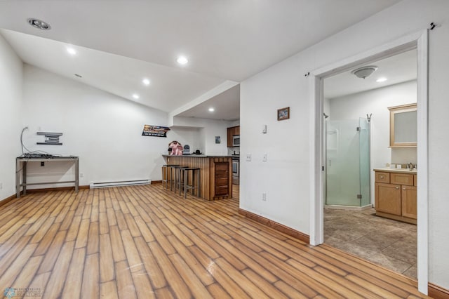 interior space featuring light wood-style flooring, recessed lighting, a baseboard radiator, baseboards, and indoor bar