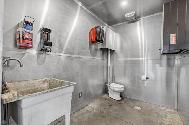 bathroom featuring electric panel, toilet, unfinished concrete flooring, and a sink