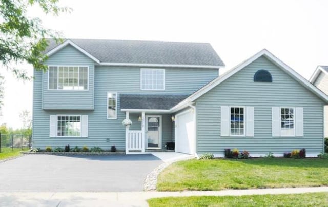 view of front of home featuring a garage, a front lawn, driveway, and fence