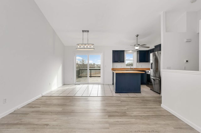 kitchen with light wood-type flooring, wooden counters, a ceiling fan, and stainless steel fridge with ice dispenser