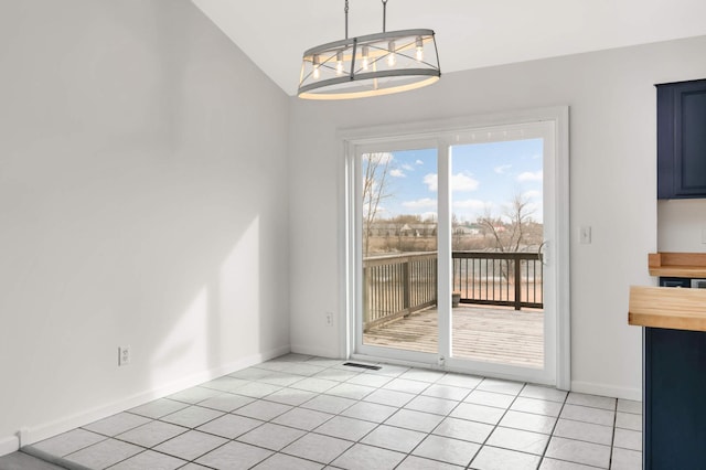 unfurnished dining area with light tile patterned floors, baseboards, and vaulted ceiling