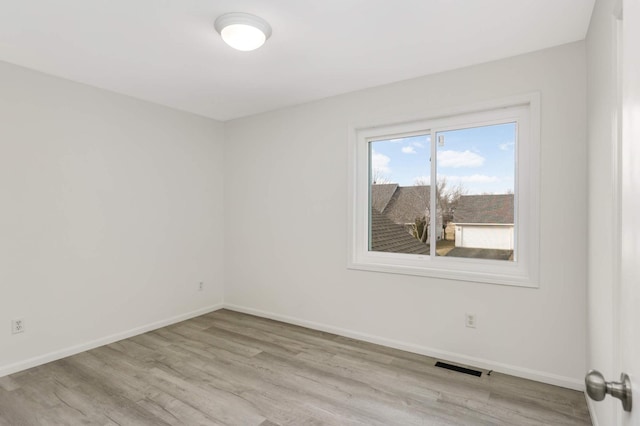 unfurnished room with visible vents, baseboards, and wood finished floors