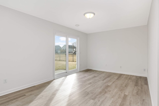 unfurnished room with light wood-type flooring and baseboards