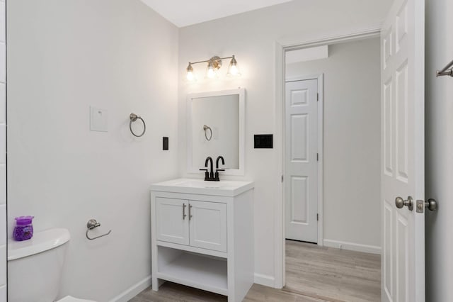 bathroom featuring vanity, toilet, wood finished floors, and baseboards