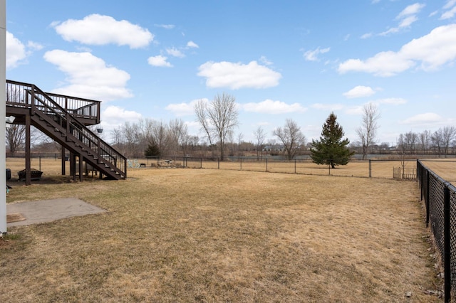 view of yard featuring a rural view, a wooden deck, stairs, and fence