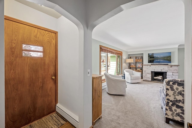 entrance foyer with a stone fireplace, light carpet, arched walkways, and a baseboard radiator