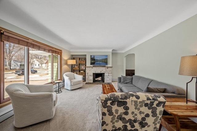 carpeted living room with arched walkways, a fireplace, and a baseboard radiator