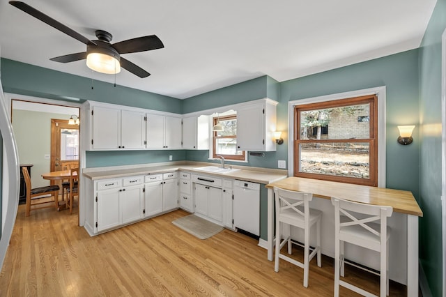 kitchen with white cabinets, light countertops, light wood-style floors, and white dishwasher