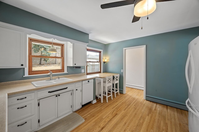 kitchen featuring white appliances, light wood finished floors, a sink, white cabinetry, and a baseboard heating unit