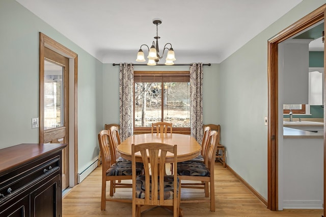 dining space with a baseboard heating unit, an inviting chandelier, baseboards, and light wood finished floors