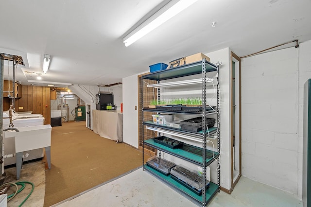 finished basement featuring gas water heater, concrete block wall, and a sink