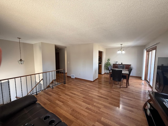 interior space with visible vents, baseboards, a chandelier, wood finished floors, and a textured ceiling