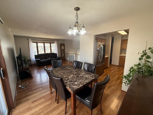 dining space with an inviting chandelier, radiator, light wood-style floors, and a textured ceiling