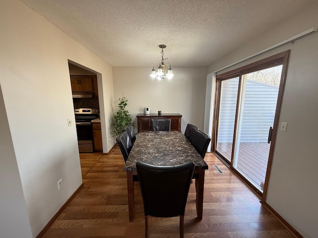 dining room featuring baseboards, a notable chandelier, wood finished floors, and a textured ceiling