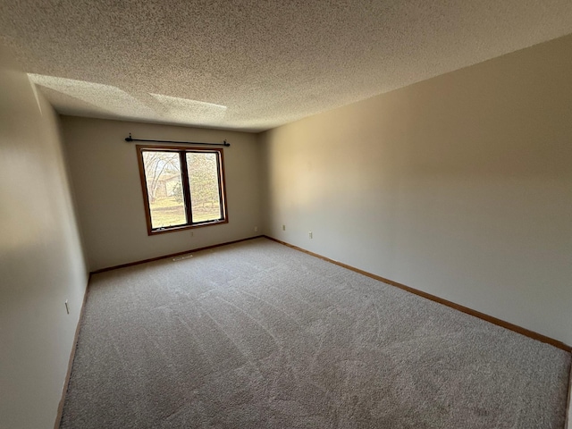 spare room with visible vents, light colored carpet, a textured ceiling, and baseboards