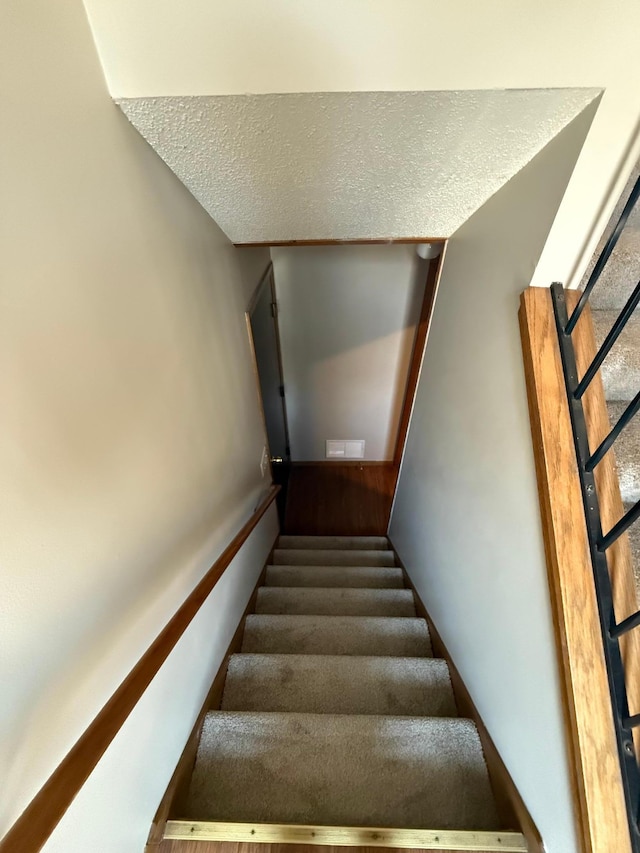 stairway featuring a textured ceiling