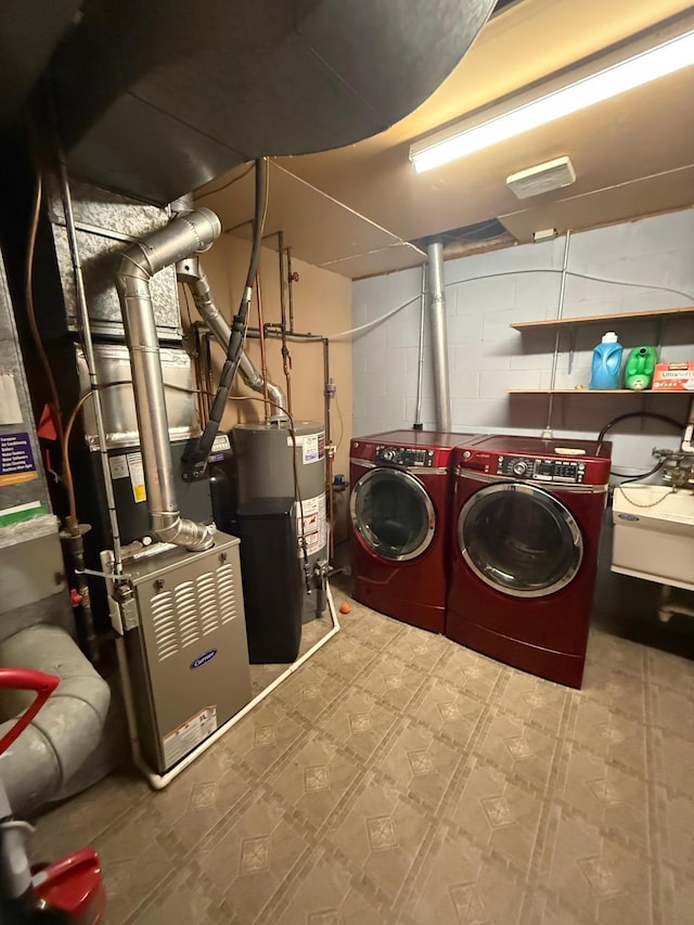 laundry room featuring water heater, tile patterned floors, washer and dryer, concrete block wall, and a sink