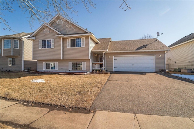 tri-level home featuring aphalt driveway, a garage, central AC unit, and a front lawn