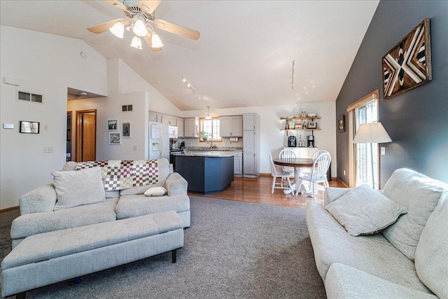 living room with high vaulted ceiling, wood finished floors, visible vents, and ceiling fan