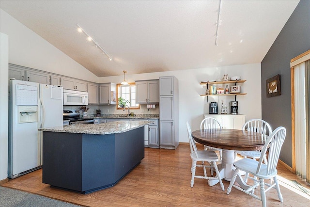 kitchen featuring a kitchen island, vaulted ceiling, gray cabinets, white appliances, and a sink