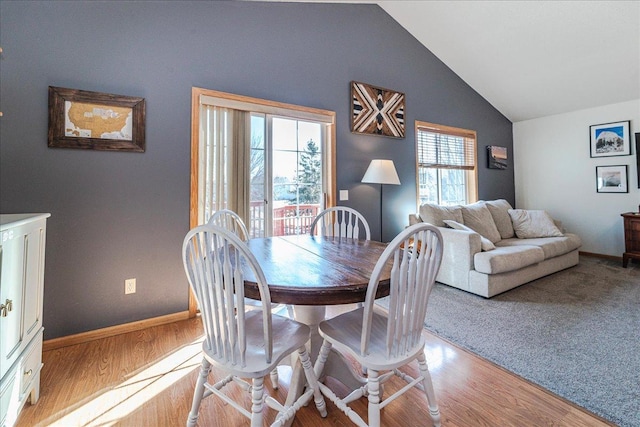 dining room featuring lofted ceiling, wood finished floors, and baseboards