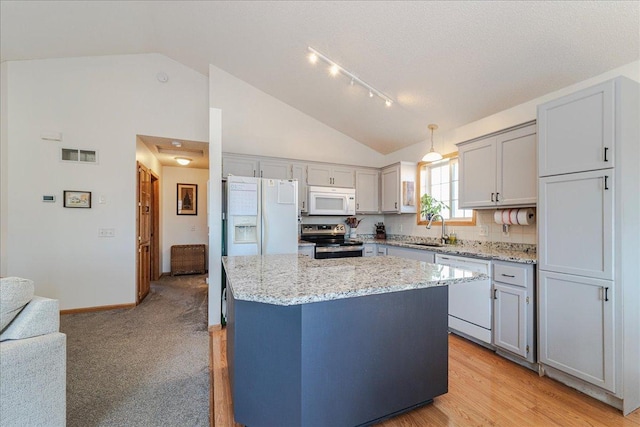 kitchen with visible vents, a sink, light stone counters, a kitchen island, and white appliances