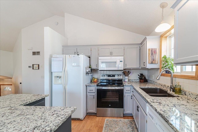 kitchen featuring a sink, white appliances, light wood finished floors, and vaulted ceiling