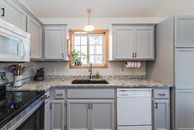 kitchen with white appliances, gray cabinetry, backsplash, and a sink