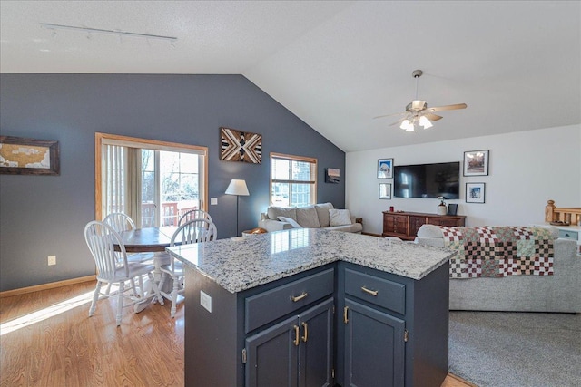 kitchen with a ceiling fan, baseboards, lofted ceiling, light wood-style floors, and open floor plan