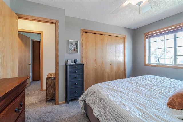 carpeted bedroom featuring a ceiling fan, a closet, and a textured ceiling