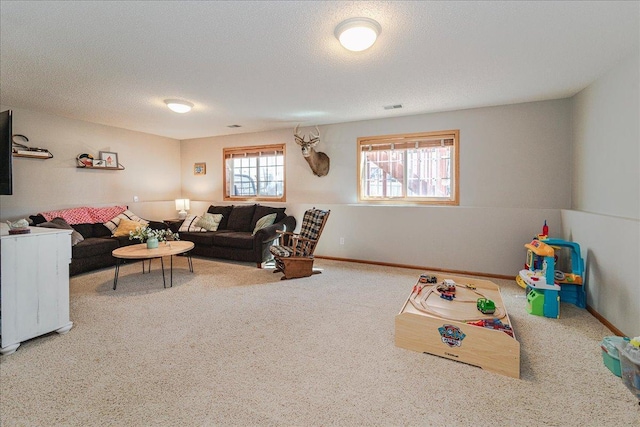 living area with visible vents, baseboards, a textured ceiling, and carpet flooring