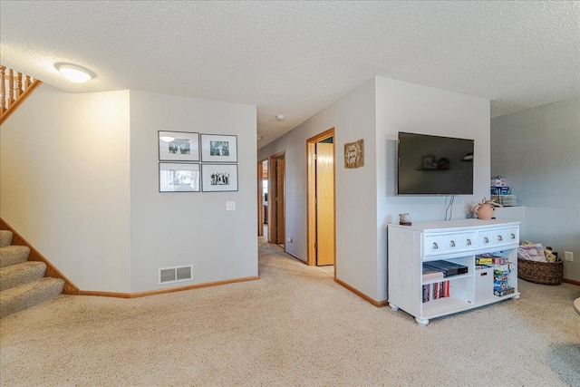 living room with visible vents, light colored carpet, stairs, and a textured ceiling