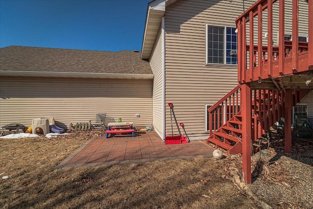 view of home's exterior with a patio and roof with shingles