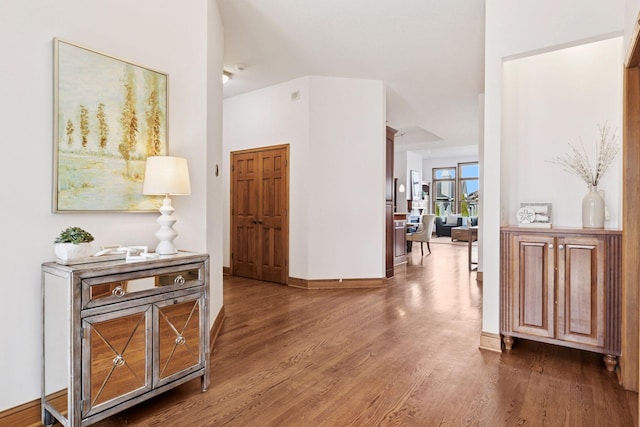 corridor with baseboards and wood finished floors