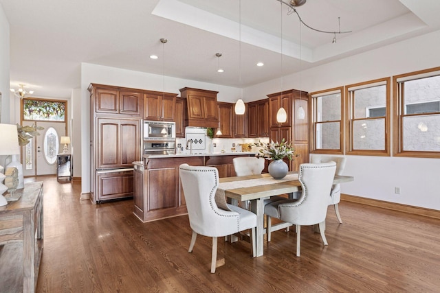 dining area with recessed lighting, baseboards, dark wood-type flooring, and a tray ceiling