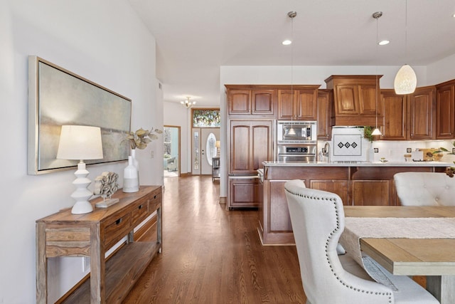 kitchen featuring decorative light fixtures, a kitchen bar, light countertops, dark wood-style floors, and stainless steel appliances