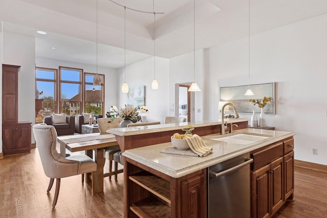 kitchen featuring a sink, open shelves, stainless steel dishwasher, wood finished floors, and a kitchen island with sink