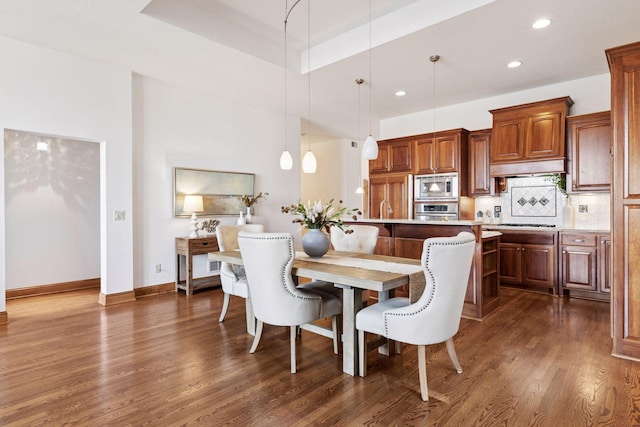 dining room featuring dark wood finished floors, recessed lighting, a tray ceiling, and baseboards