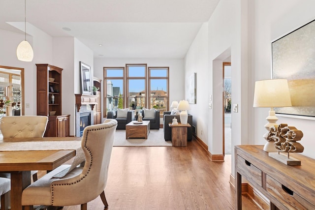 dining space with a glass covered fireplace, baseboards, and light wood-type flooring