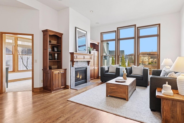 living area with a fireplace, light wood-type flooring, and baseboards