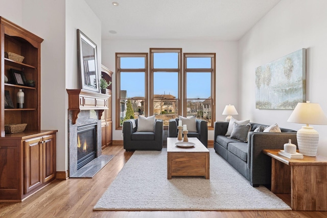 living area with light wood-type flooring, baseboards, and a premium fireplace