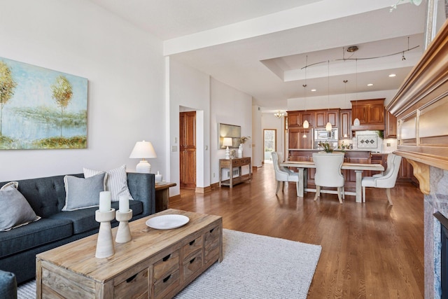 living area featuring a tray ceiling, a fireplace, dark wood-style flooring, and baseboards