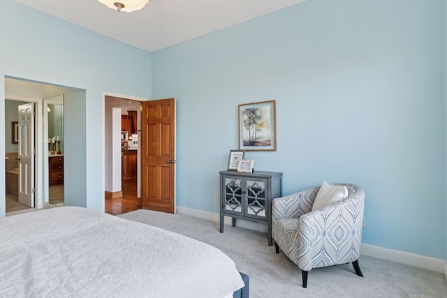 bedroom with light colored carpet, ensuite bath, and baseboards