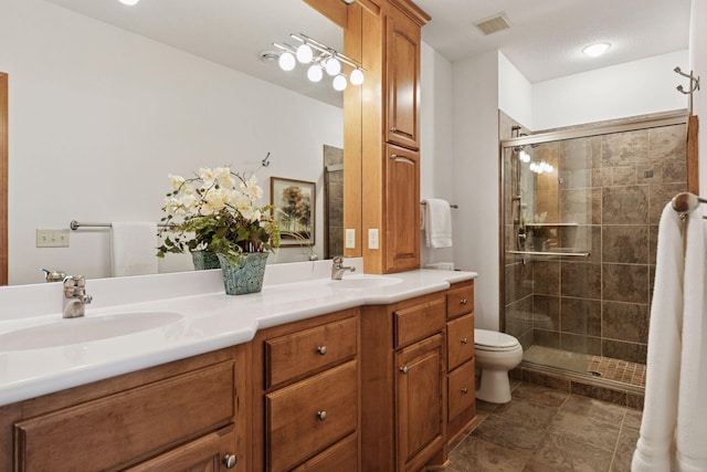 bathroom featuring double vanity, visible vents, a shower stall, and a sink